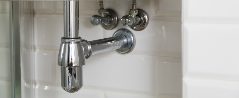 Pipe system under a sink in a bathroom.