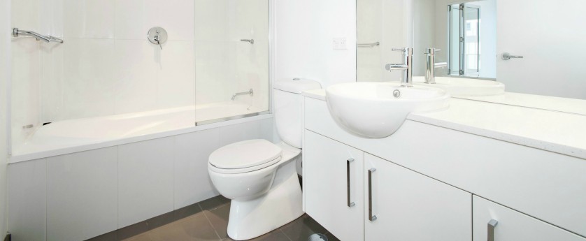 Modern bathroom with white tile, cabinets, and walls.